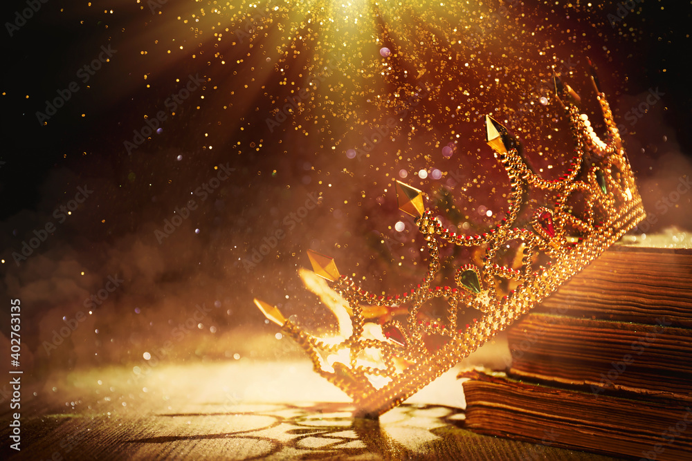 Wall mural fantasy world. beautiful golden crown and old books lit by magic light on table