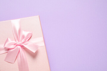 Pink gift box on violet background, top view. Space for text