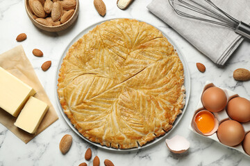 Traditional galette des rois and ingredients on white marble table, flat lay