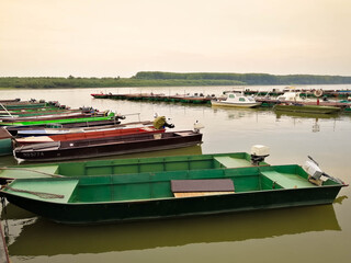 Old rusty fishing boats docked on Danube river, in a row, horizon line in the background