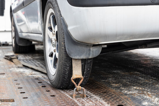 Close-up of car wheel tied with safety harness on flatbed tow truck