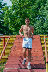 Obraz premium Sexy topless athlete running down the stairs in a park on a summer day
