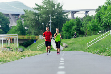 Young running couple jogging on an asphalt road in the park