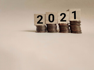 Business Concept - 2021 written on wooden blocks with coins background. Stock photo.