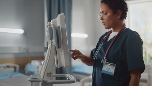 Hospital Ward: Beautiful Black Female Head Nurse, Doctor, Surgeon Uses Health Care Vitals Monitoring Computer Machine. Modern High Tech Clinic with Advanced Equipment and Professional Staff