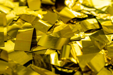 Confetti in shiny gold color lying as a background, golden foil particles flakes texture structure
