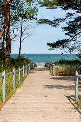 Walkway down to the white sand beach at the Baltic Sea coast in Binz on Rügen Island, beautiful sunny day with blue sky and colorful teal water