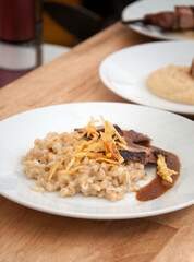 Serving plate with roasted meat, pearl barley and roasted onions
