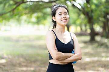 Fototapeta premium Portrait of sport woman with arms cross, wearing sportswear, happy and smiling after working out. Woman, sport and exercise outdoor concept