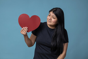 Mexican latin girl holding  a red heart shaped paper valentine's day