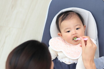 リビングで離乳食を食べさせてもらう赤ちゃん