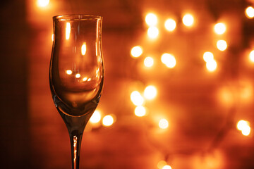 Empty champagne glass with candlelit background in a romantic setting. Romanticism, toast, festivity concept.