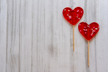 Valentine's card. Two Lollipops as heart on wooden background. Banner of sweet heart shaped candies on white background. Love concept. 