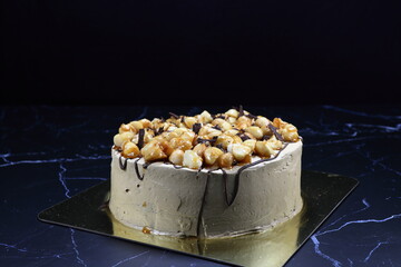 Classic coffee cake topping with macadamia nut and chocolate serving on the golden tray. Famous traditional baked dessert in party. 