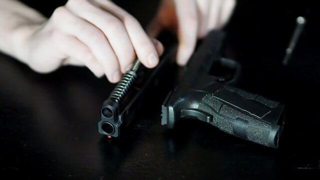 Hands of a gunsmith working on a striker-fired pistol