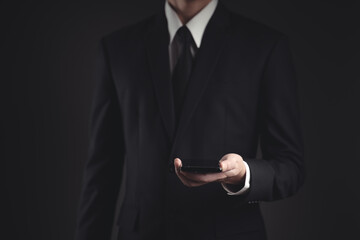 Businessman showing smart phone in black suit.