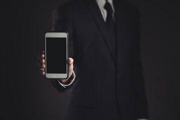 Businessman showing smart phone in black suit.