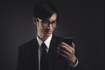 Businessman in black suit happy looking at smart phone.
