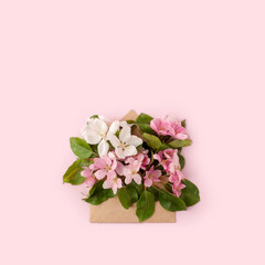 Flat-lay of paper craft envelope with white pink apple blossom flowers over pastel light pink background, top view. Spring or summer mood concept, 8 march woman day, Happy Easter card, copy space