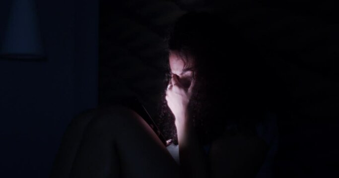Dramatic lifestyle of young sad and depressed Latin American woman crying in bed holding mobile phone victim of cyber bullying or broken heart in her bedroom. 4K.