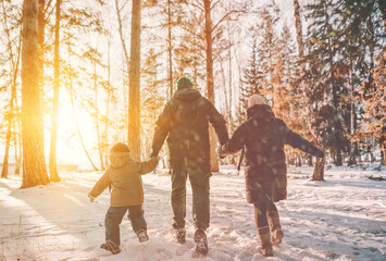 Family walking in winter forest park in snowfall