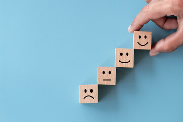 Close up top view customer hand choose smiley face on wood cube, Service rating, satisfaction...