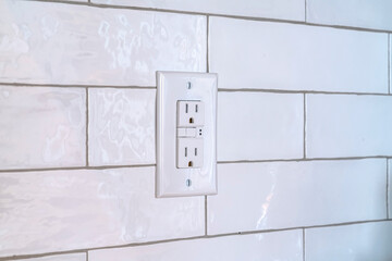 Grounded outlet for electric appliances against white tile wall inside a home