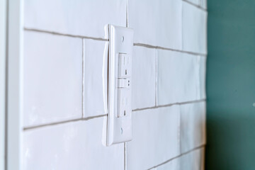 Home interior with close up view of a grounded outlet installed on the tile wall