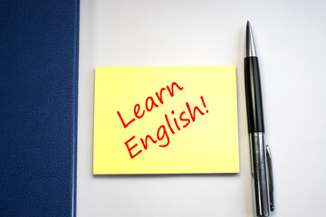 Learn English written on a yellow sheet near which is a blue notepad and pen. The concept of learning and education