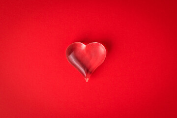 A glass heart on a bright red background.