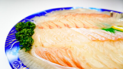 Raw fish flounder sashimi slice (flatfish sashimi) set on a take-out plate. Isolated on white background.