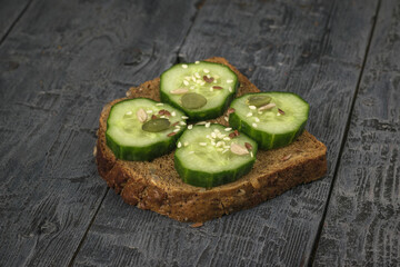 Four slices of cucumber on a piece of bread with pumpkin seeds and sunflower seeds.