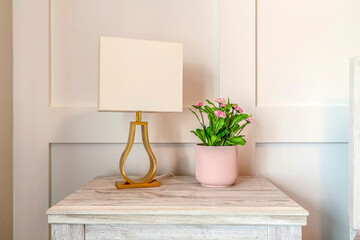 Modern lampshade and potted plant with flowers on the wooden side table