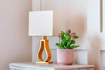 Bedroom interior with potted flowering plant and modern lamp shade against wall