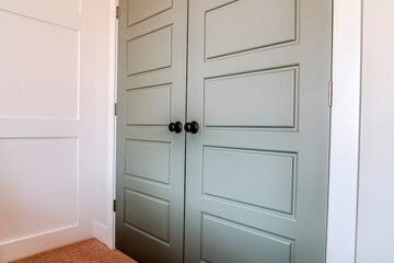 Double doors with hinges and black round doorknob at the bedroom entrance