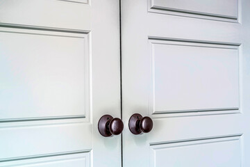 Hinged wooden interior double doors with panelled design and round doorknobs