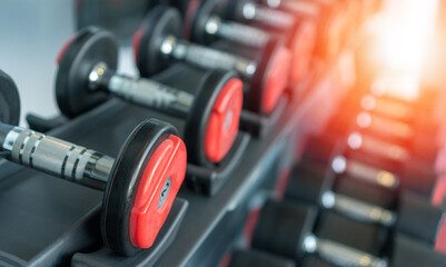 Fototapeta na wymiar Dumbbells in modern fitness gym with light effect. View of weight training body builder equipment in workout room.Defocus dumbbell in exercise place.