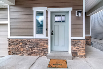 Glass paned front door and sidelight against brick wall and wood siding of home