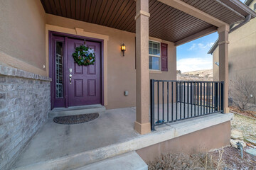 Vibrant purple front door with sidelight and wreath at the facade of home