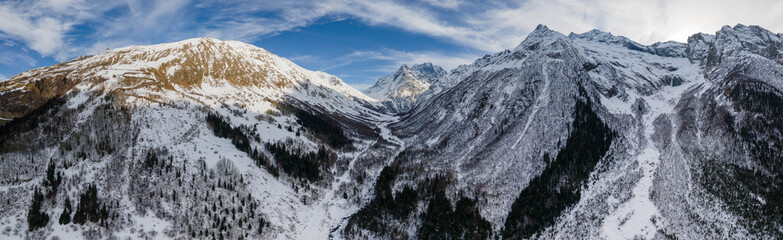 Fototapeta na wymiar Aerial panorama from a drone of winter mountains and snow-capped hills. Location Dobay, Russia
