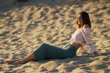 Fototapeta na wymiar Smiling woman sitting on the sand of the beach