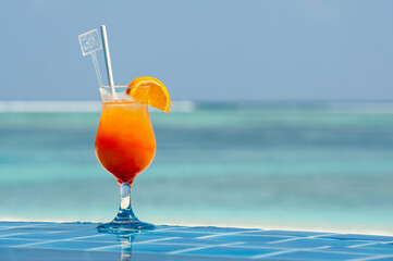 Orange Tropical Cocktails near the Swimming Pool on Background of Warm turquoise ocean. Exotic Summer Vacation.