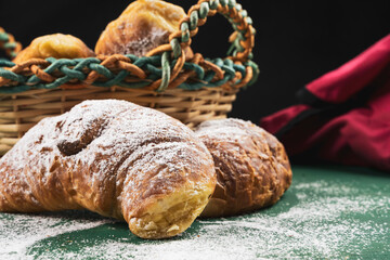 freshly baked croissants with powdered sugar on a rustic table