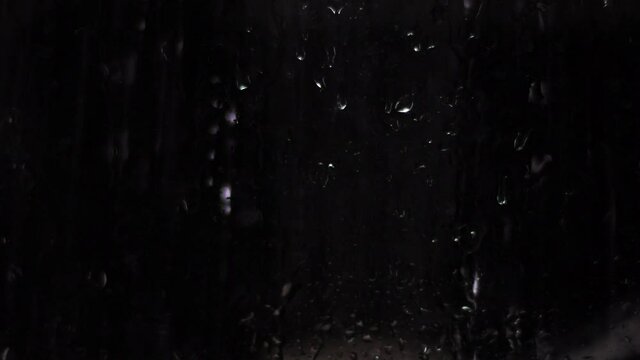 Background with raindrops on a black background for overlay to create mood. Light water on glass isolated on a dark background.