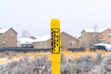 Pole marker with warning sign for natural gas pipeline buried underground