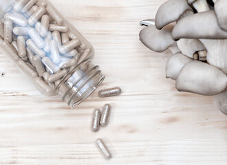 mushrooms and a bottle with mushroom capsules supplement on a table. antioxidant and detoxifying nutritional supplement. vegan superfood.  © Yulia Panova
