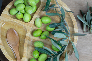 Fresh olives and olive oil on rustic wooden background. Olives in olive wood.