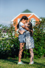 Fototapeta premium Two happy girl friends in nature. Friendly teenage girls cuddle on a summer afternoon on the lawn. Friendship and warm relations of children