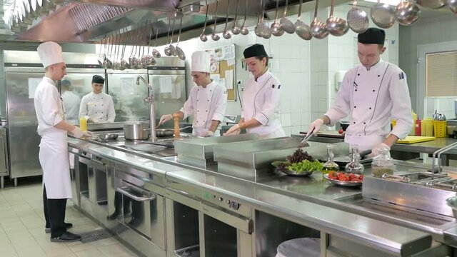 Cooks prepare meals on an electric stove in a professional kitchen in a restaurant or hotel