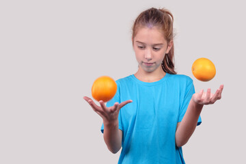 A girl in blue shirt juggling oranges